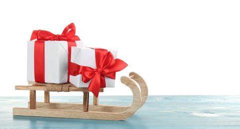 Decorative sleigh with Christmas gift boxes on light blue wooden table. Space for text