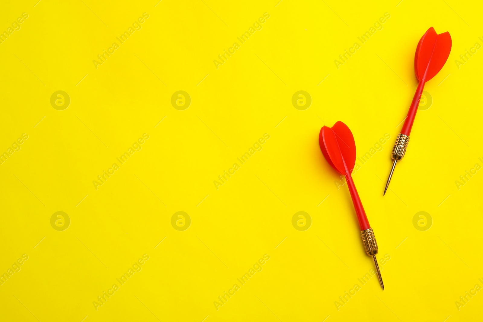 Photo of Red dart arrows on yellow background, flat lay with space for text