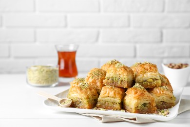 Delicious fresh baklava with chopped nuts on white table, space for text. Eastern sweets