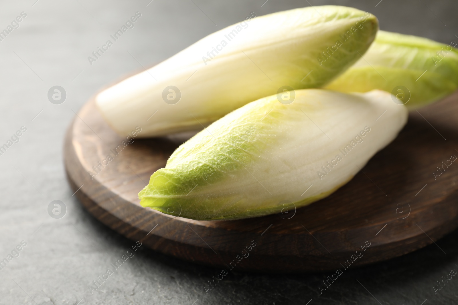 Photo of Fresh raw Belgian endives (chicory) on black table, closeup