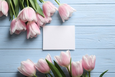 Beautiful tulips and card for Mother's Day on wooden background, top view