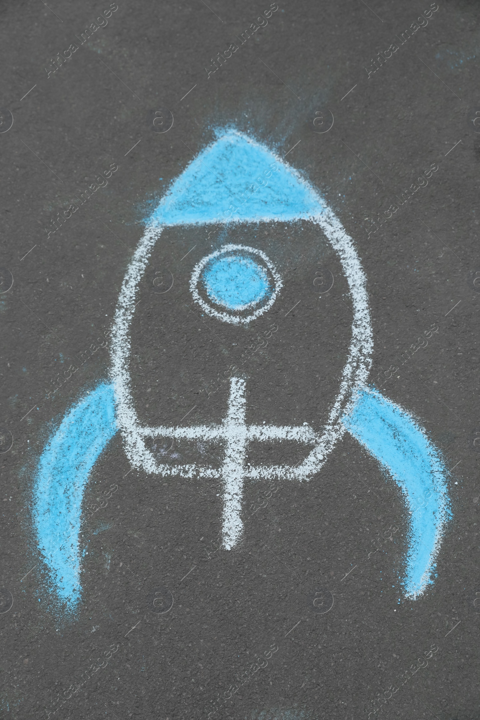 Photo of Child's chalk drawing of rocket on asphalt, above view