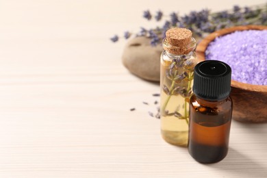 Bowl of sea salt, essential oil and lavender flowers on white wooden table, closeup. Space for text