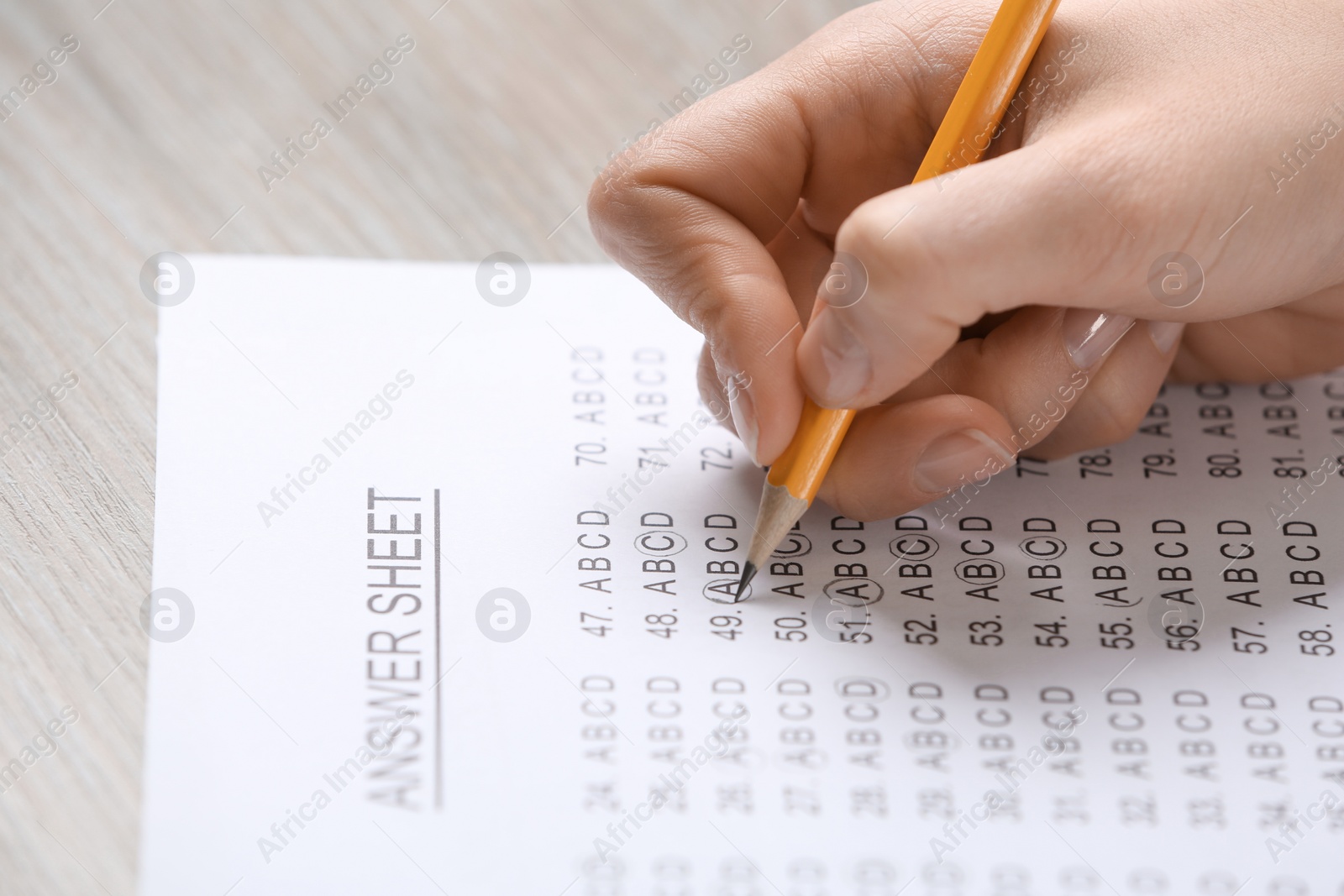 Photo of Student filling answer sheet at table, closeup