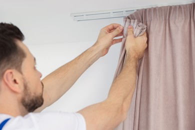 Worker hanging window curtain, closeup of hands