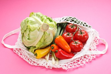 String bag with different vegetables on bright pink background