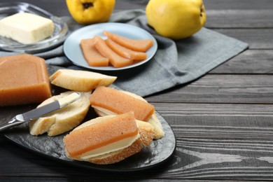 Photo of Tasty sandwiches with quince paste served on black wooden table, space for text