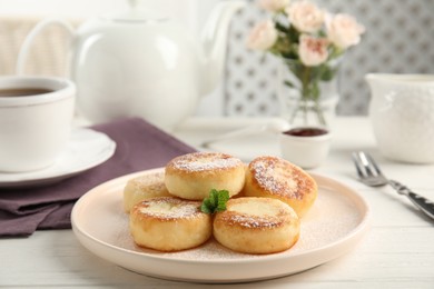 Photo of Delicious cottage cheese pancakes with mint and icing sugar on white wooden table