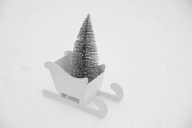 Photo of White wooden sleigh with decorative fir tree on snow outdoors