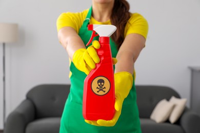 Woman showing bottle of toxic household chemical with warning sign, closeup