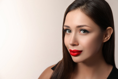 Beautiful woman with red lipstick on light background, space for text