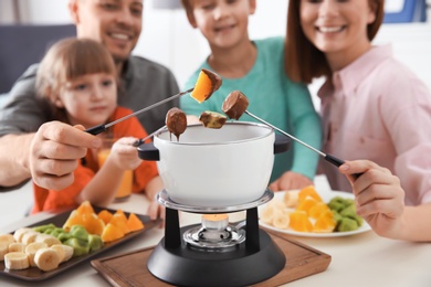 Photo of Happy family enjoying fondue dinner at home, selective focus
