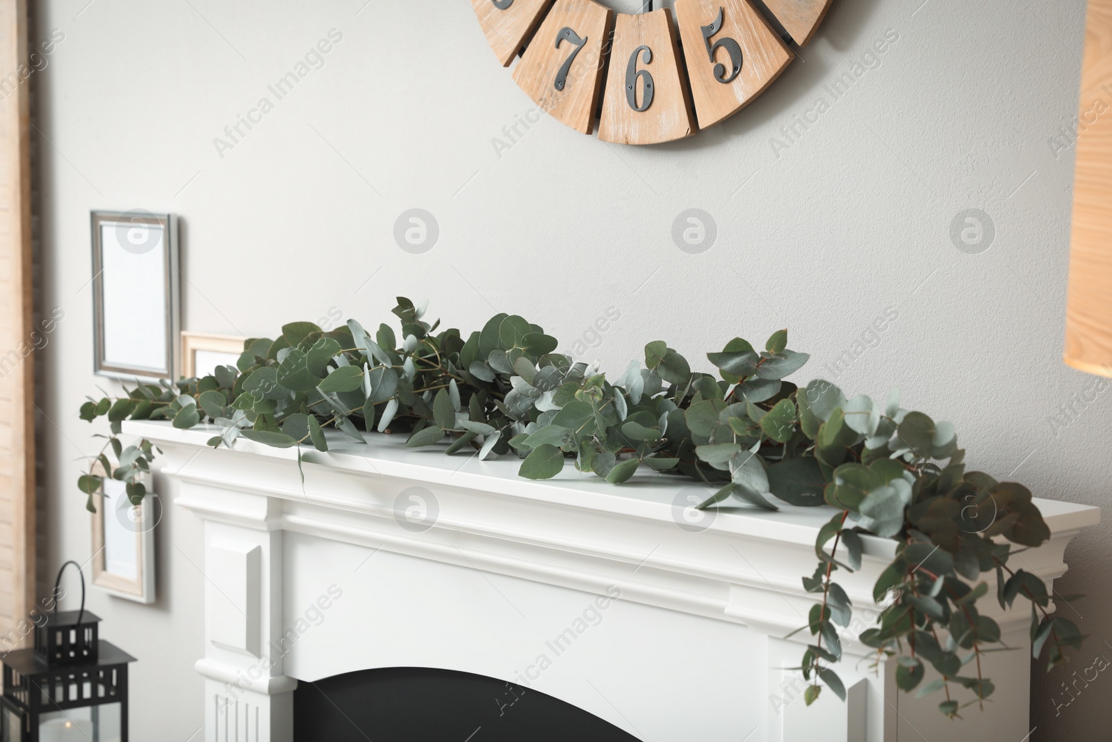 Photo of Beautiful garland with eucalyptus branches on mantelpiece in room