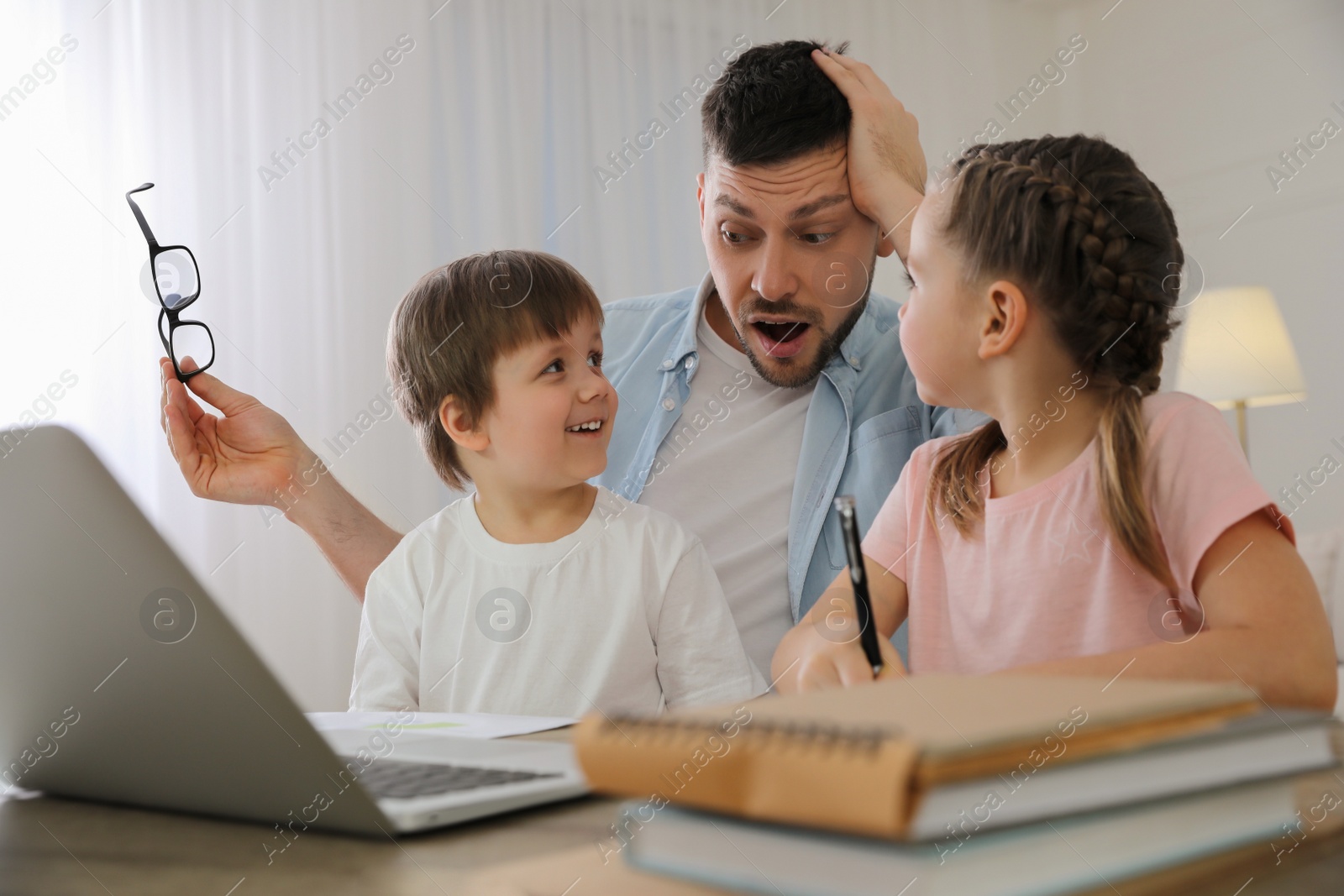 Photo of Overwhelmed man combining parenting and work at home