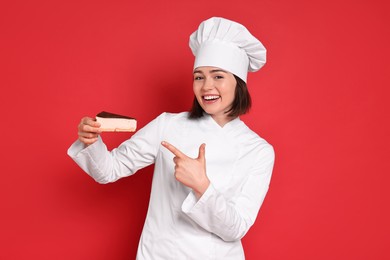 Photo of Happy confectioner with cheesecake on red background