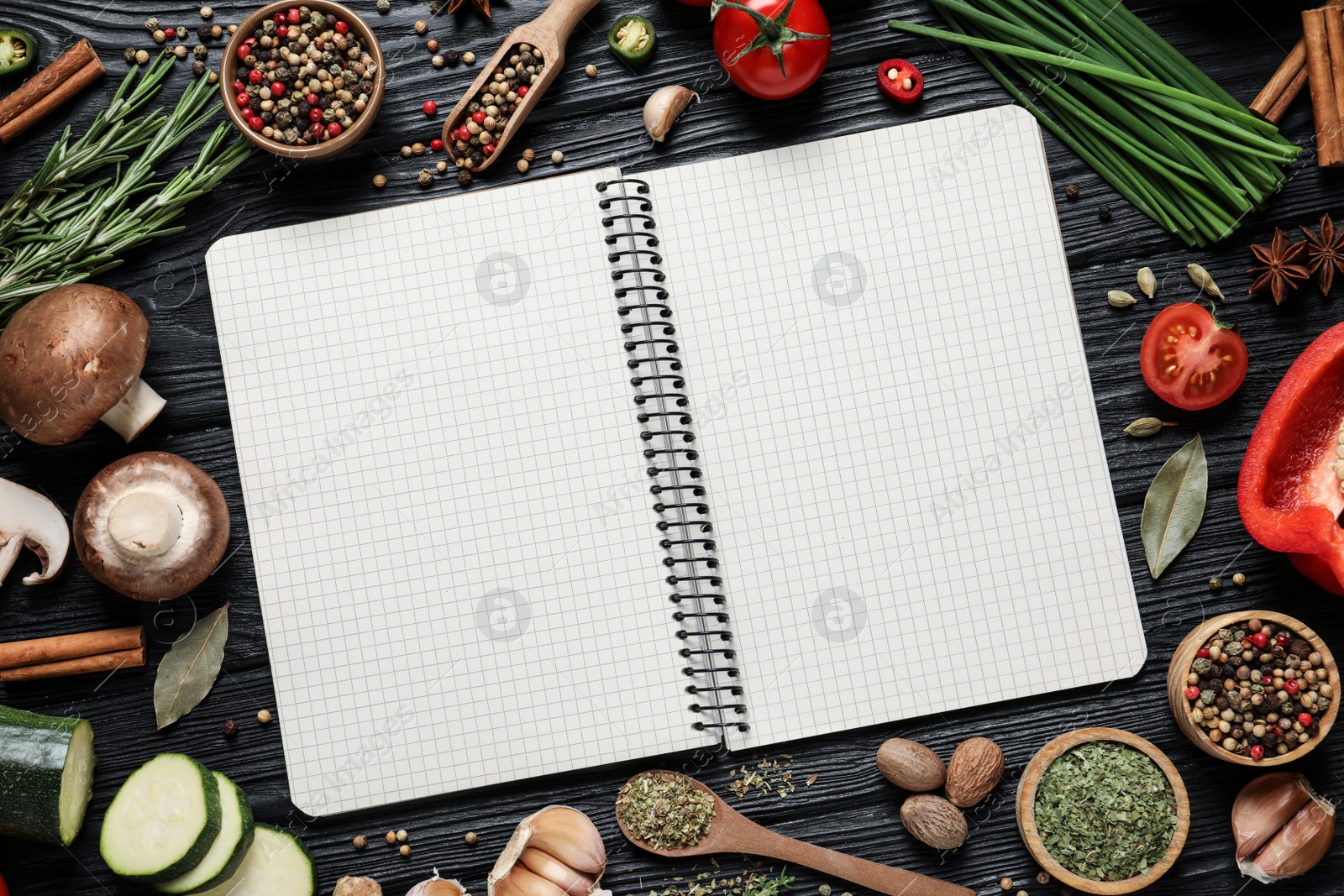 Photo of Open recipe book and different ingredients on black wooden table, flat lay. Space for text