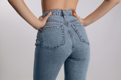 Woman in stylish jeans on light background, closeup