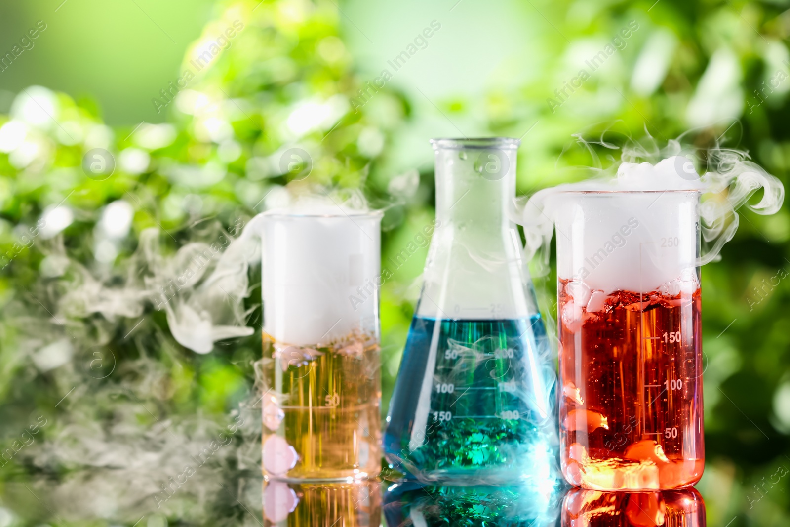 Photo of Laboratory glassware with colorful liquids on glass table outdoors. Chemical reaction