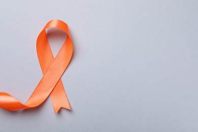 Orange ribbon on light grey background, top view with space for text. Multiple sclerosis awareness