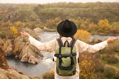 Photo of Woman with travel backpack enjoying nature near mountain river, back view