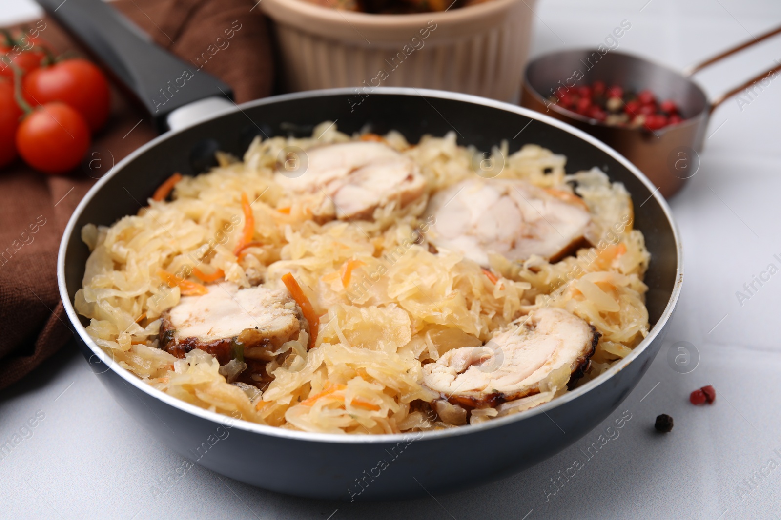 Photo of Frying pan with sauerkraut, and chicken on white tiled table