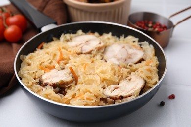 Frying pan with sauerkraut, and chicken on white tiled table