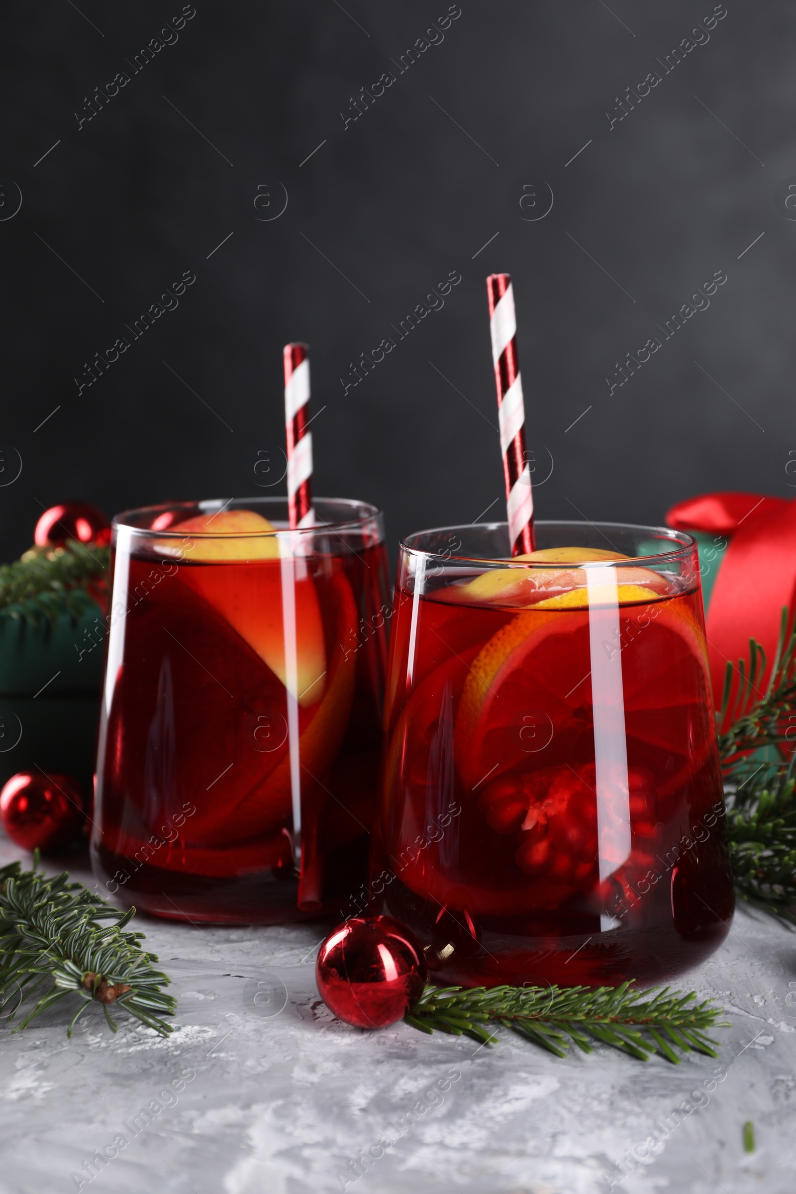 Photo of Delicious Sangria drink in glasses and Christmas decorations on grey textured table, closeup