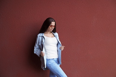 Photo of Young hipster woman in stylish jeans and jacket posing near color wall