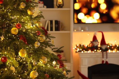 Photo of Beautiful decorated Christmas tree and festive decor on fireplace in living room, selective focus