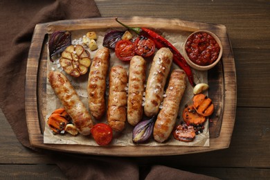 Tasty grilled sausages and products on wooden table, top view