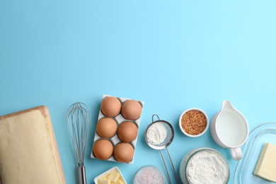 Photo of Puff pastry dough and ingredients on light blue background, flat lay. Space for text