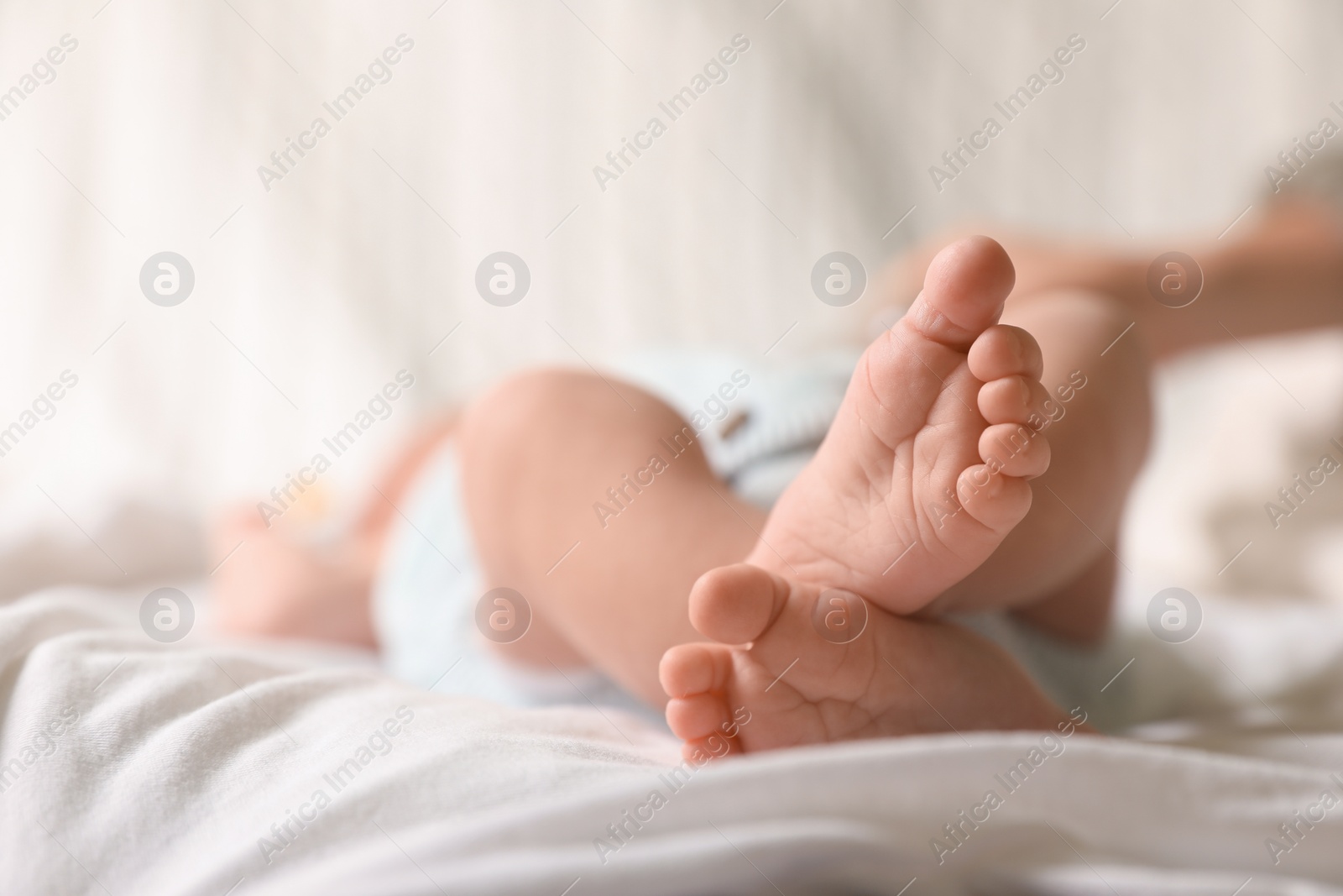 Photo of Cute newborn baby lying on bed, closeup of legs. Space for text