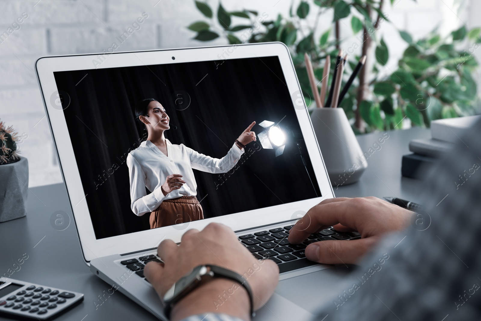 Image of Man watching performance of motivational speaker on laptop at grey table, closeup