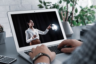 Image of Man watching performance of motivational speaker on laptop at grey table, closeup