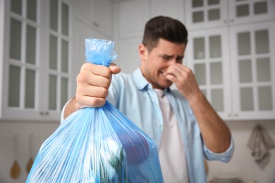 Photo of Man holding full garbage bag at home, focus on hand