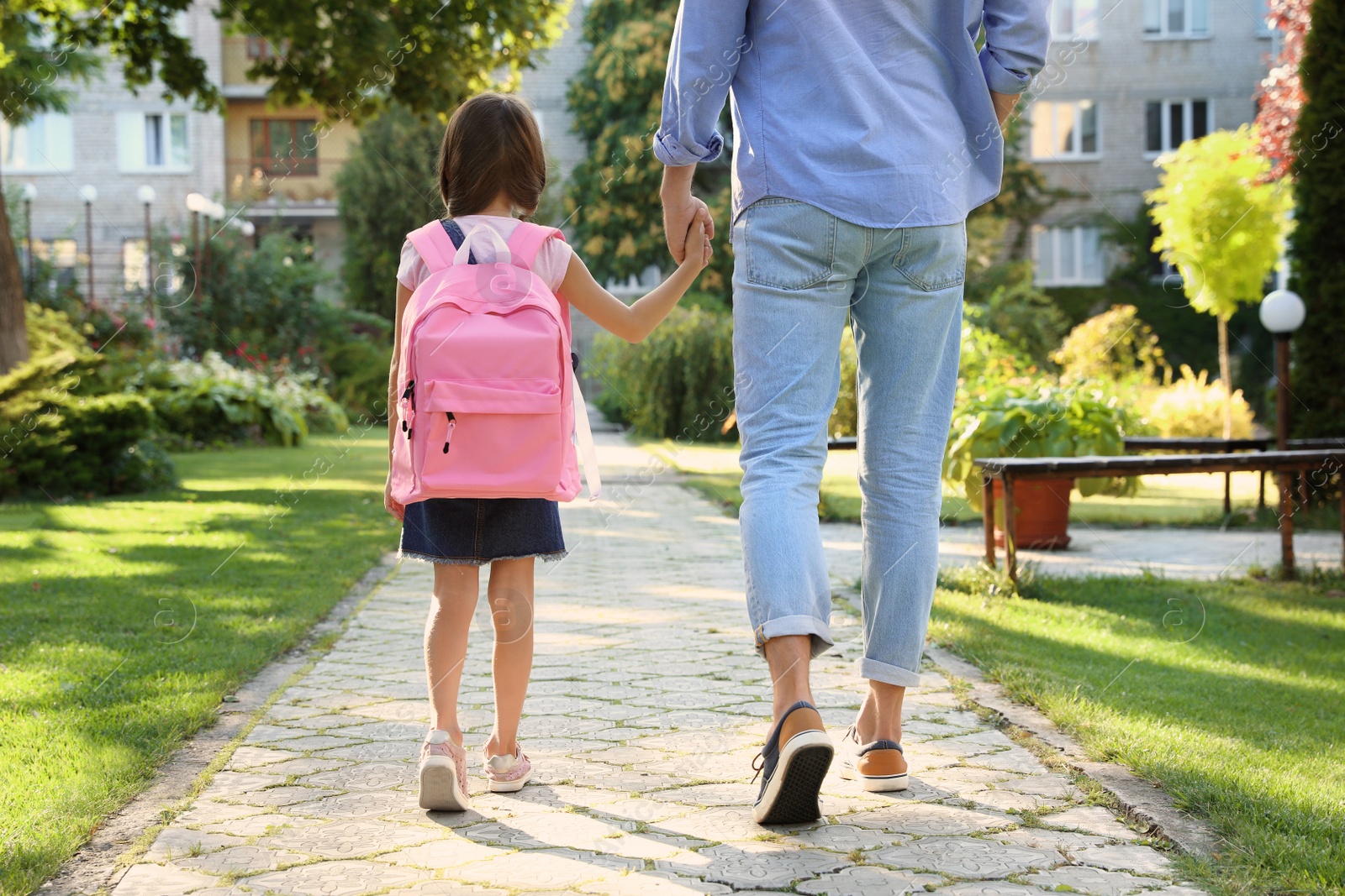 Photo of Father taking his little child to school through park