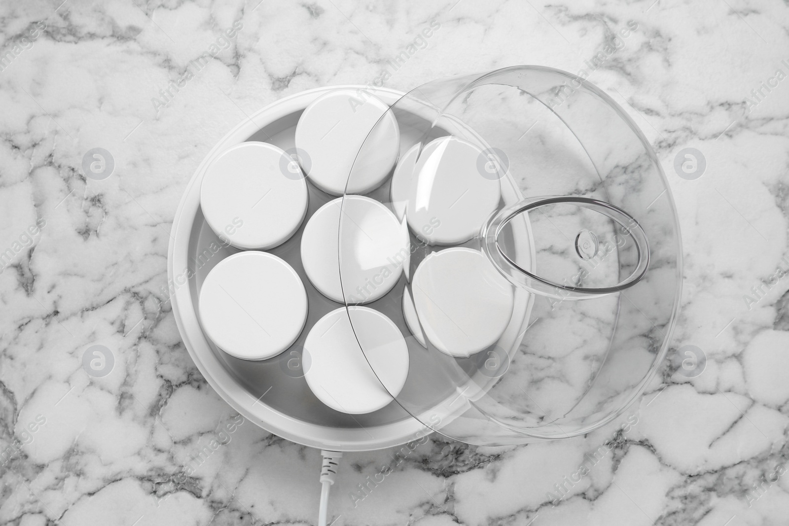 Photo of Modern yogurt maker with jars on white marble table, top view