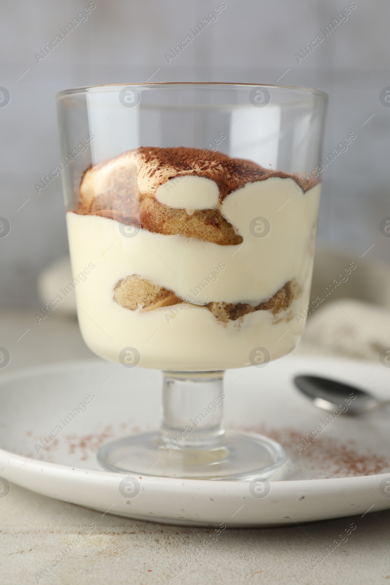 Photo of Delicious tiramisu in glass on light table