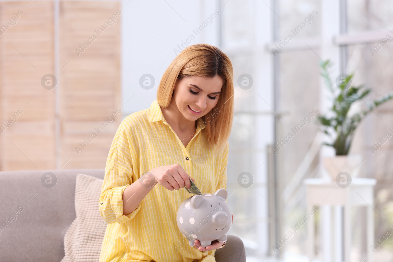 Photo of Woman with piggy bank and money at home