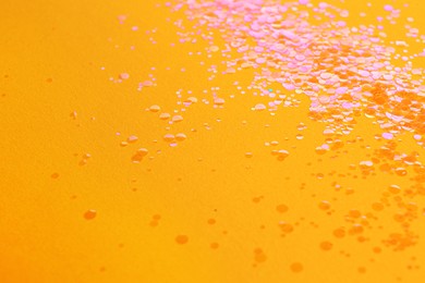 Photo of Pile of shiny bright glitter on orange background