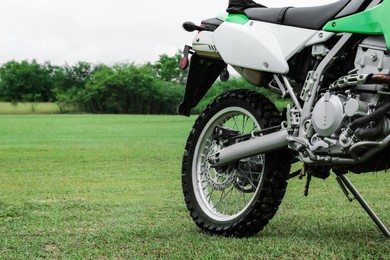 Photo of Cross motorcycle on green grass outdoors, closeup. Space for text
