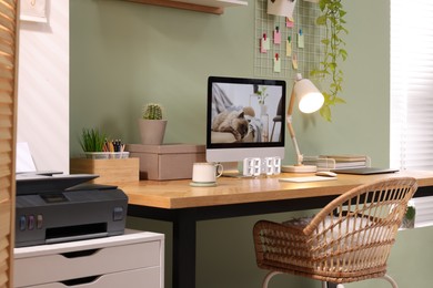 Photo of Stylish workplace with computer, laptop and lamp near olive wall at home