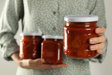 Photo of Woman holding jars of canned lecho, closeup