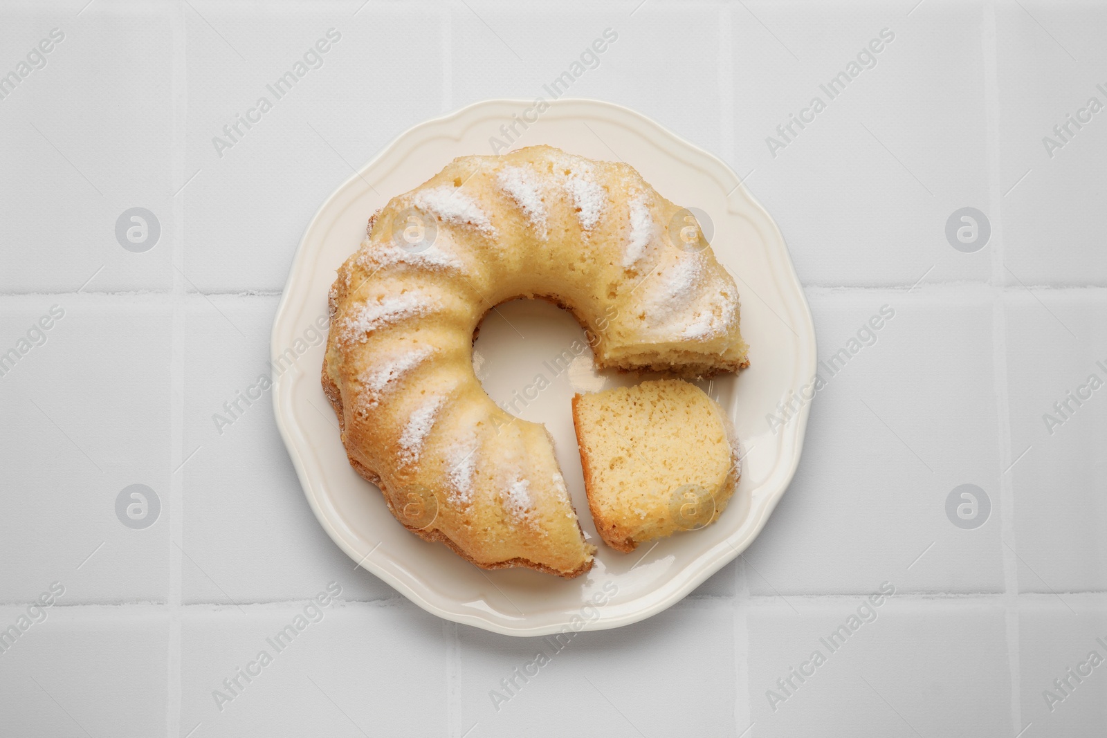 Photo of Delicious freshly baked sponge cake on white tiled table, top view