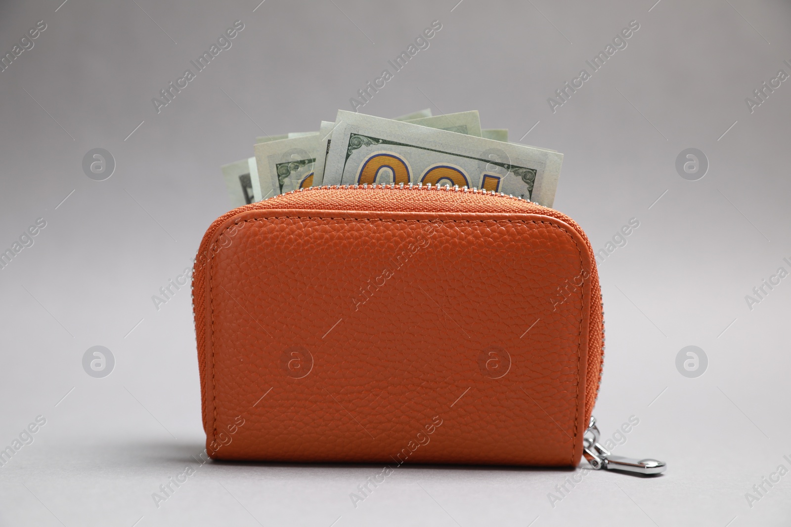 Photo of Stylish brown leather purse with dollar banknotes on light grey background