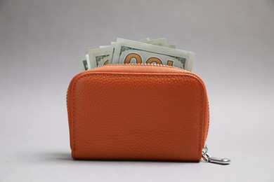 Stylish brown leather purse with dollar banknotes on light grey background
