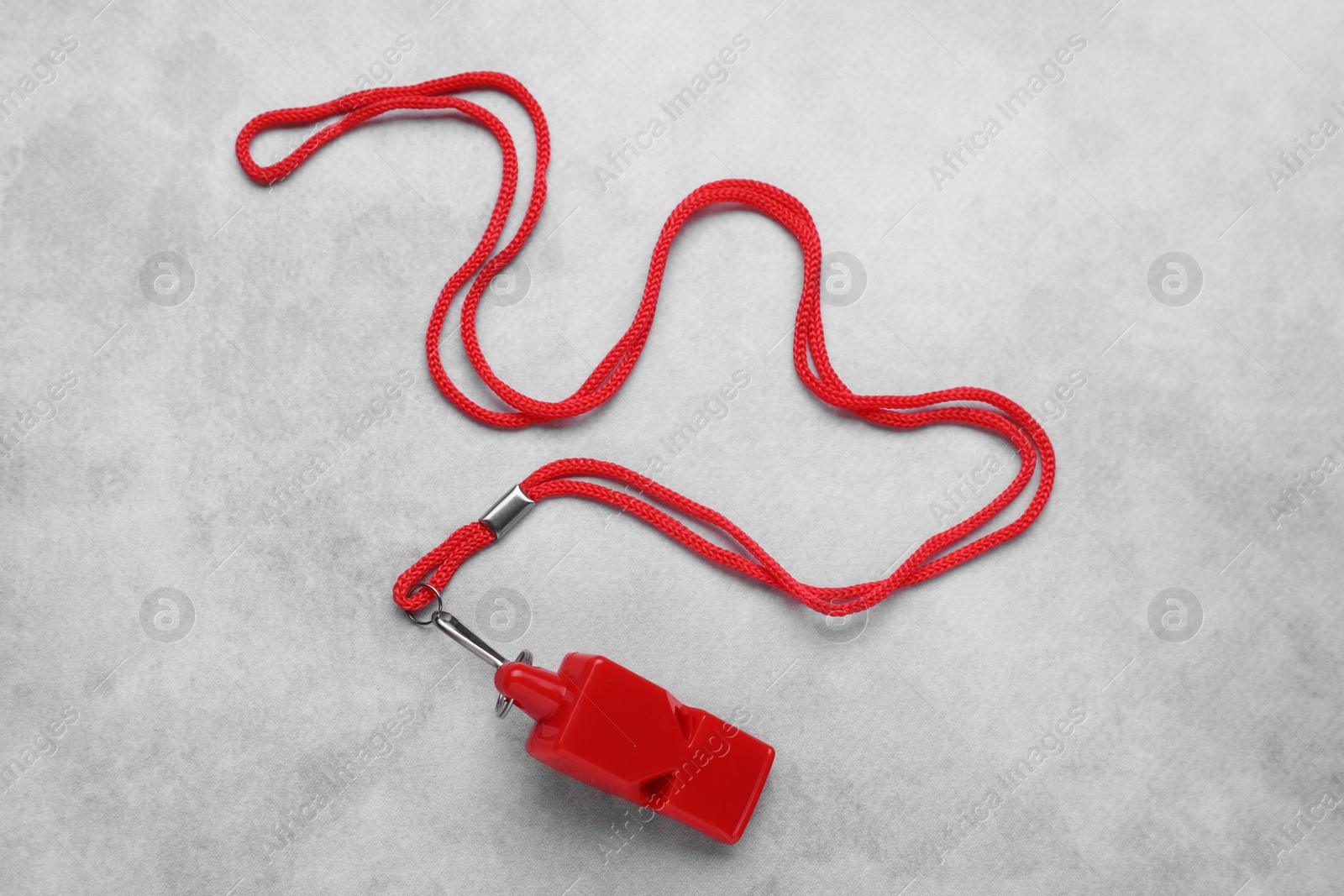 Photo of One red whistle with cord on light grey table, top view