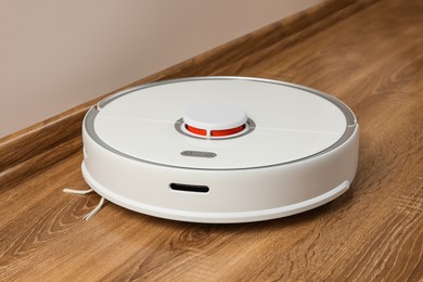 Photo of Robotic vacuum cleaner on wooden floor indoors