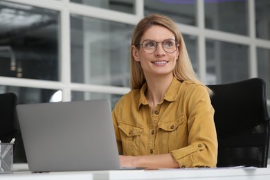 Photo of Woman working on laptop at white desk in office