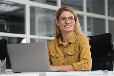 Woman working on laptop at white desk in office